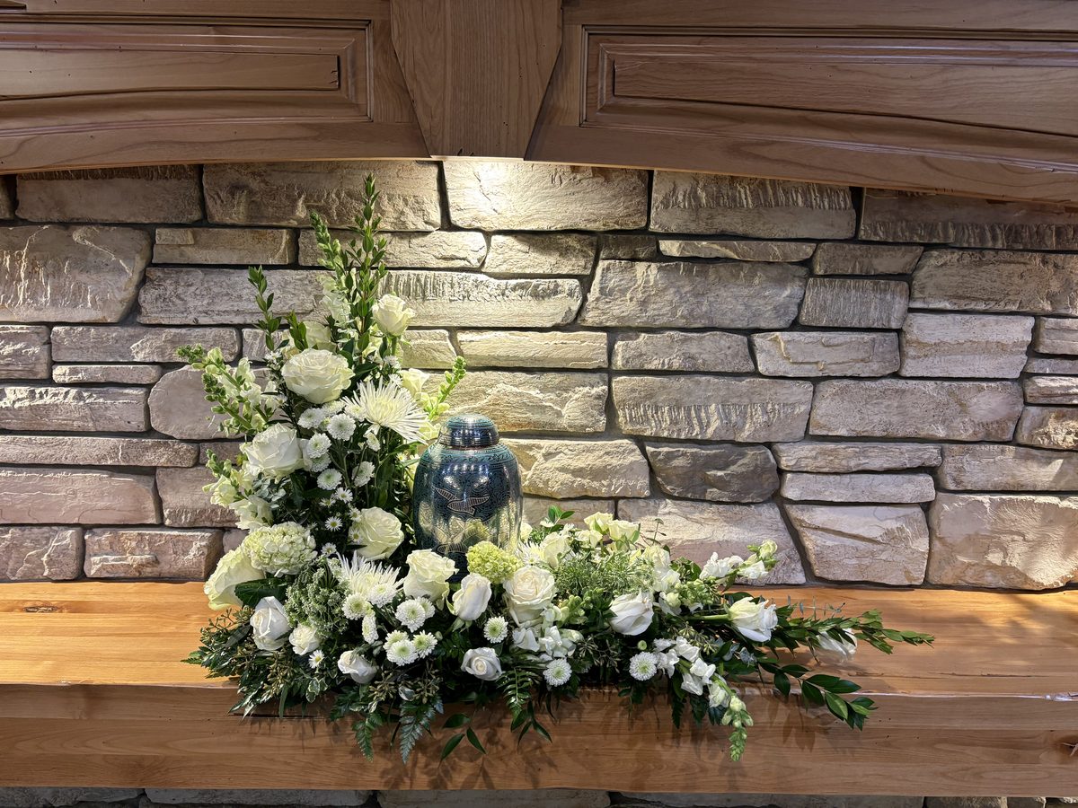 Urn Tribute - All-white arrangement with roses and snapdragons surrounding a memorial urn
